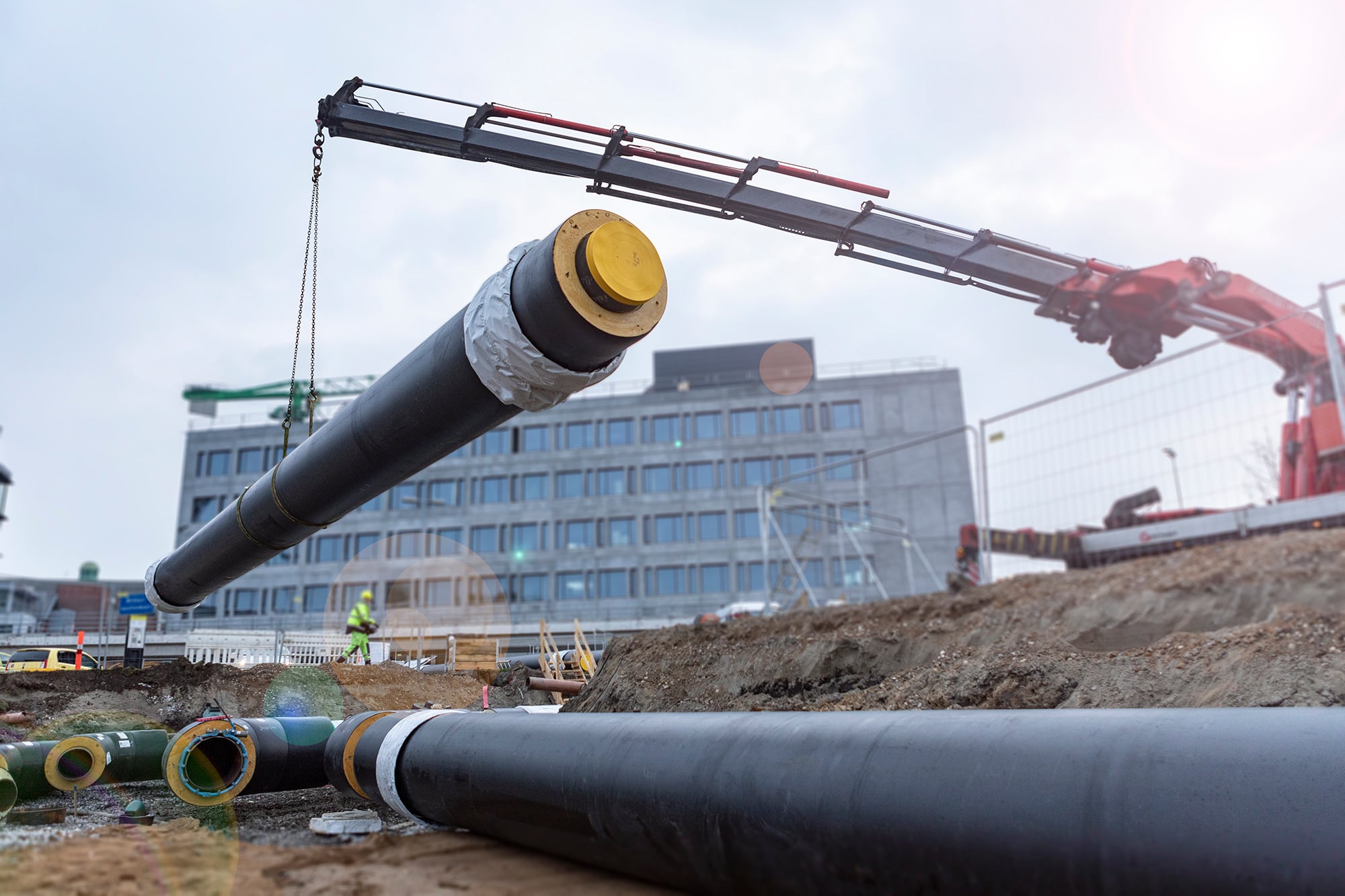 Fjernvarmerør hejses med kran på byggeplads Fjernvarmerør hejses med kran på byggeplads
